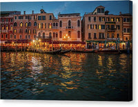 a row of buildings on the water at night