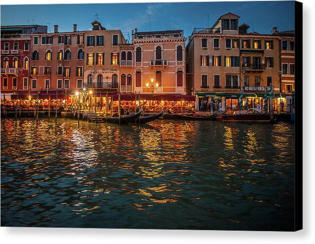 a row of buildings on the water at night