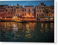 a row of buildings along the water at night