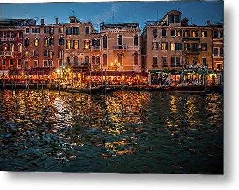 a row of buildings on the water at night