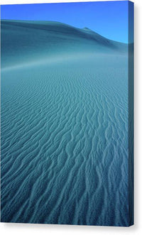 a sand dune with a blue sky in the background