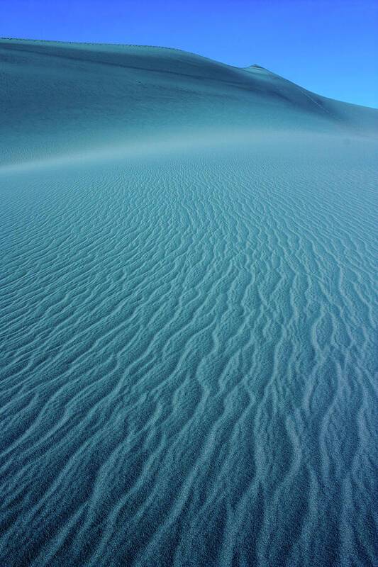 a large sand dune with a blue sky in the background